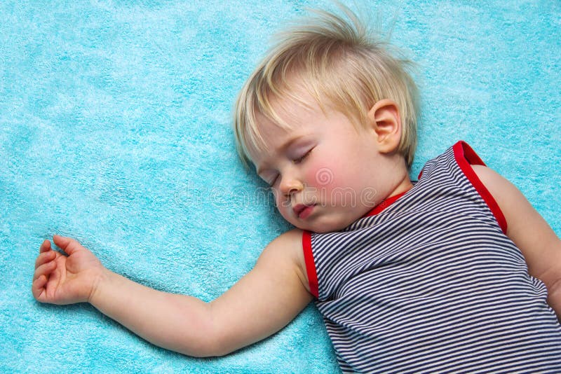 Niño cabelludo rubio durmiente en azul fotografía de archivo libre de regalías Niño cabelludo rubio durmiente en azul fotografía de archivo libre de regalías