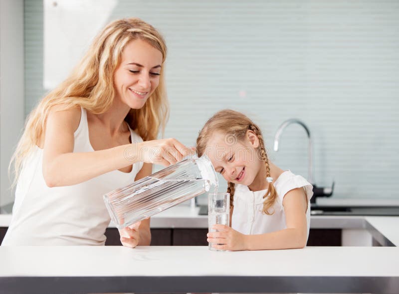 Niño con el agua potable de la madre imagen de archivo