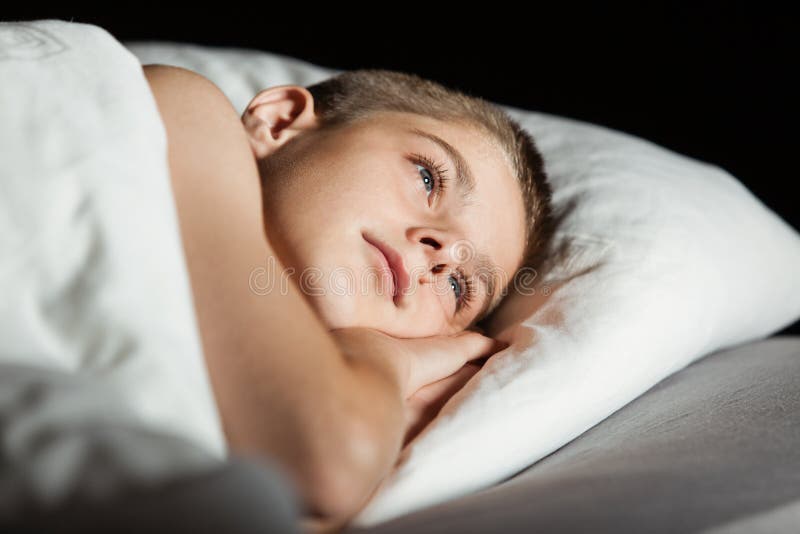 Niño con los ojos abiertos con la cabeza en la almohada fotos de archivo Niño con los ojos abiertos con la cabeza en la almohada fotos de archivo