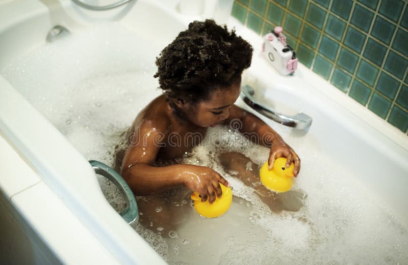 Niño de la ascendencia africana que goza de la tina de baño