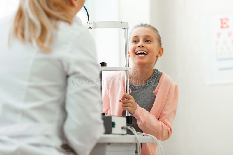 Niño emocionado alegre con sonrisa amplia que habla con el doctor agradable imagenes de archivo Niño emocionado alegre con sonrisa amplia que habla con el doctor agradable imagenes de archivo