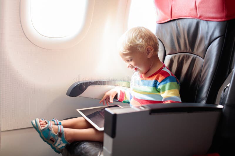 Niño en avión con equipo de tablet foto de archivo