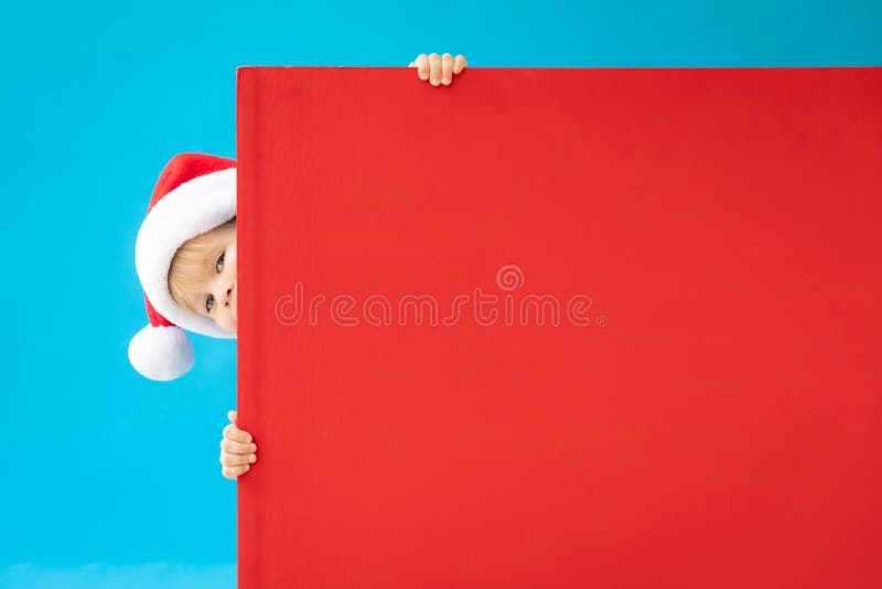 Niño feliz con banderas rojas de Navidad en blanco con fondo azul fotografía de archivo libre de regalías Niño feliz con banderas rojas de Navidad en blanco con fondo azul fotografía de archivo libre de regalías