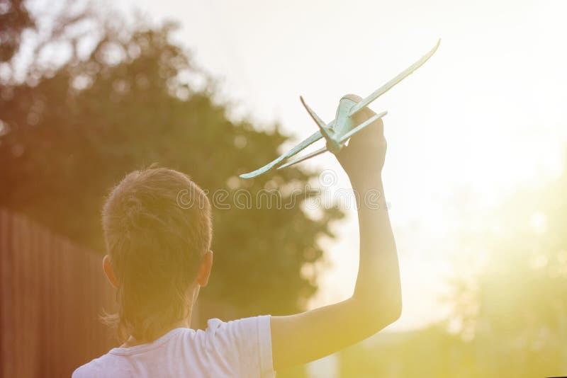 Niño feliz jugando con un avión de juguete al aire libre al atardecer fotos de archivo