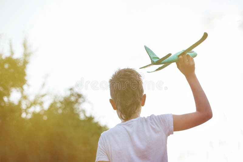 Niño feliz jugando con un avión de juguete al aire libre al atardecer fotografía de archivo