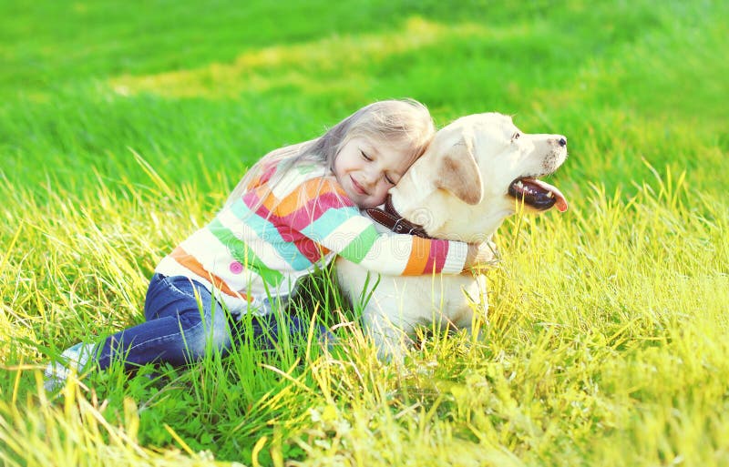 Niño feliz que abraza el perro del labrador retriever en hierba imagen de archivo libre de regalías Niño feliz que abraza el perro del labrador retriever en hierba imagen de archivo libre de regalías