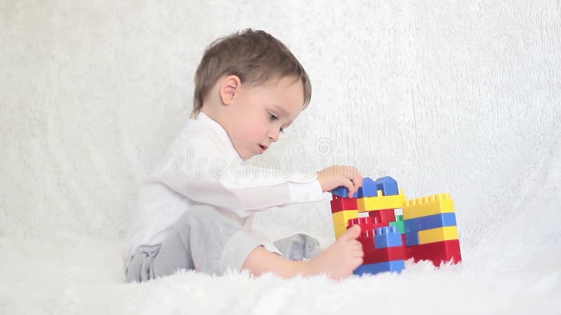 Niño feliz que juega en los bloques coloreados en el sofá