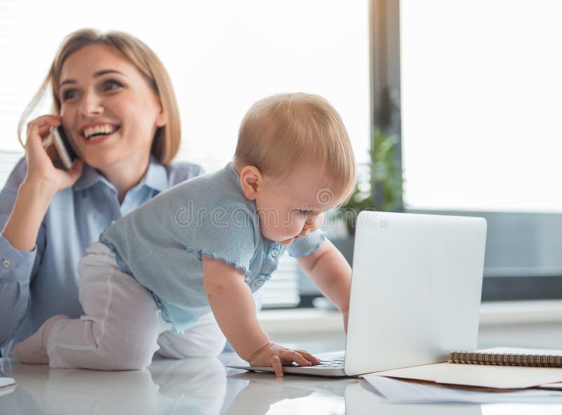 Niño interesado que juega con el ordenador cerca de mamá foto de archivo libre de regalías Niño interesado que juega con el ordenador cerca de mamá foto de archivo libre de regalías