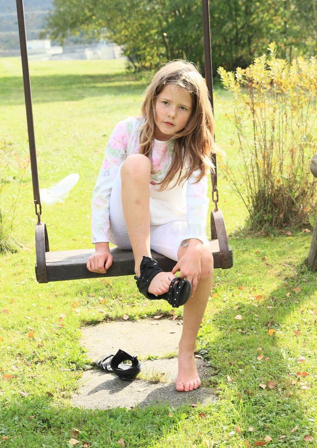 Niño - muchacha que pone en los zapatos en el oscilación fotos de archivo libres de regalías Niño - muchacha que pone en los zapatos en el oscilación fotos de archivo libres de regalías