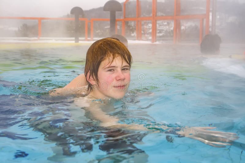 Niño nada en la piscina exterior de niebla caliente de un spa imágenes de archivo libres de regalías