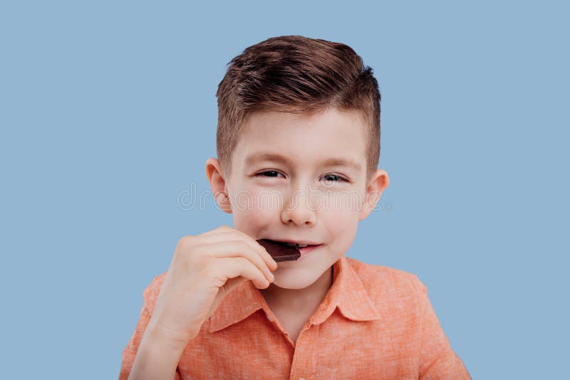 Little boy eating chocolate, isolated on blue background, in studio. Little boy eating chocolate, isolated on blue background, in studio