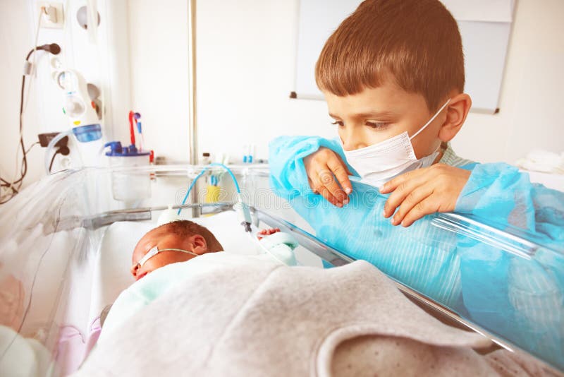Portrait of the boy and a newborn child in the hospital intensive care bed with feeding through nose, constant monitoring. Portrait of the boy and a newborn child in the hospital intensive care bed with feeding through nose, constant monitoring