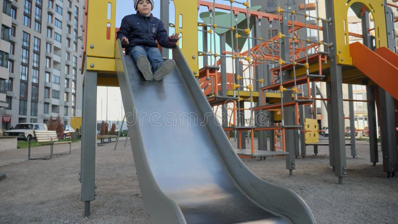 Niño pequeño deslizándose por el tobogán del patio de recreo en un patio moderno. concepto de deportes y educación para el desarro