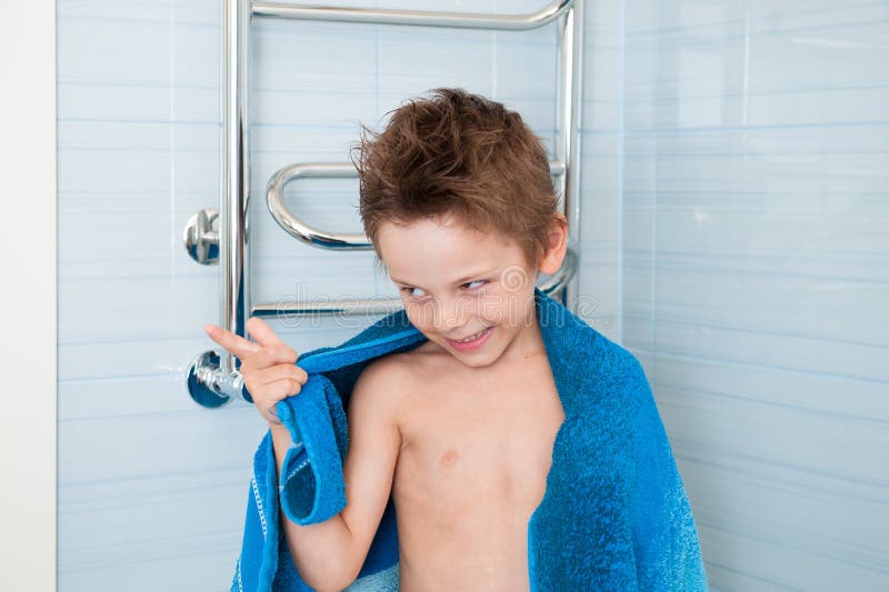 Niño pequeño divertido lindo con la toalla en sus hombros y el pelo mojado en cuarto de baño azul fotografía de archivo libre de regalías Niño pequeño divertido lindo con la toalla en sus hombros y el pelo mojado en cuarto de baño azul fotografía de archivo libre de regalías