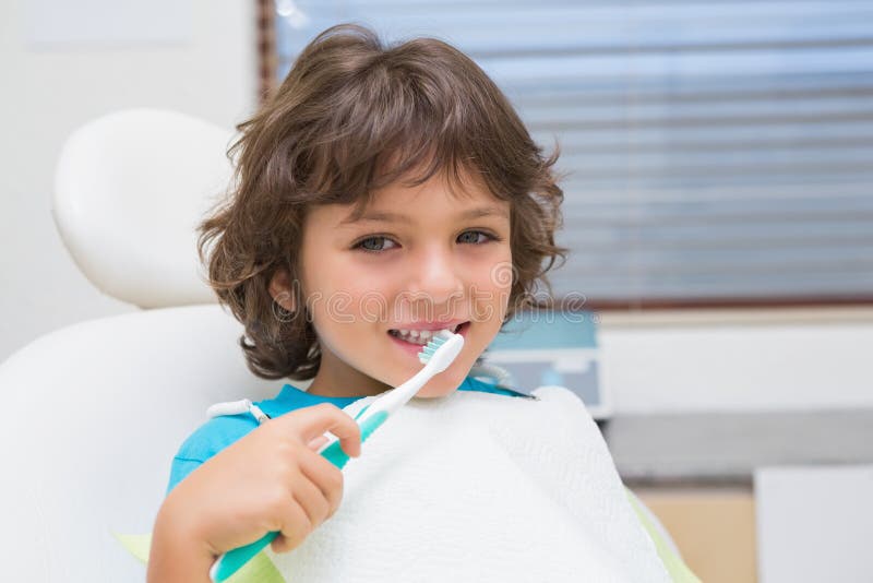 Little boy in dentists chair using toothrbrush at the dental clinic. Little boy in dentists chair using toothrbrush at the dental clinic