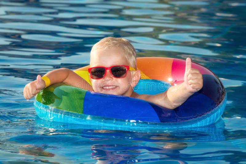 Niño pequeño feliz que juega con el anillo inflable colorido en piscina al aire libre en día de verano caliente Los niños aprende imágenes de archivo libres de regalías Niño pequeño feliz que juega con el anillo inflable colorido en piscina al aire libre en día de verano caliente Los niños aprende imágenes de archivo libres de regalías