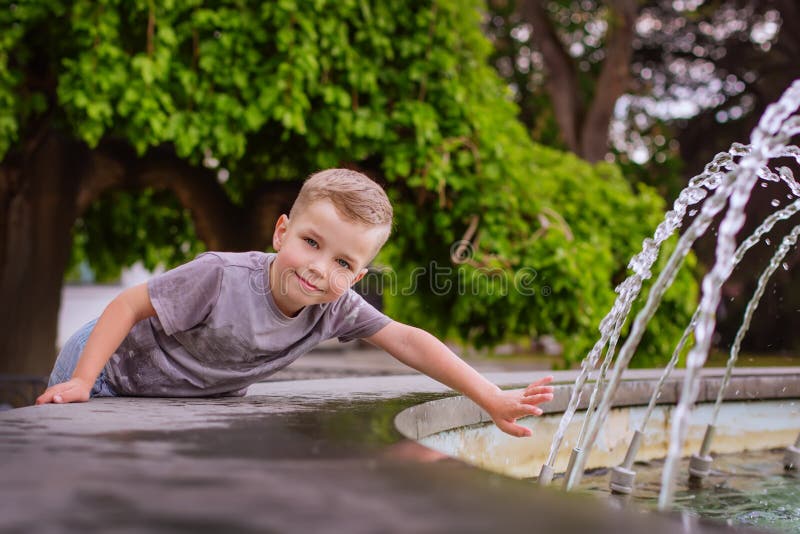 Niño pequeño lindo que juega con una fuente fotografía de archivo libre de regalías Niño pequeño lindo que juega con una fuente fotografía de archivo libre de regalías