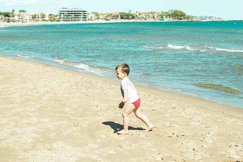 Niño pequeño que camina a lo largo de la playa imagenes de archivo Niño pequeño que camina a lo largo de la playa imagenes de archivo