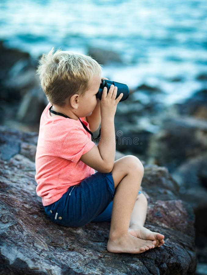 Niño pequeño que mira lejos con los prismáticos foto de archivo Niño pequeño que mira lejos con los prismáticos foto de archivo
