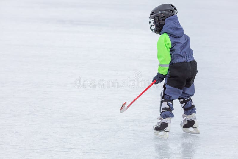 Niño pequeño que patina y que juega a hockey foto de archivo Niño pequeño que patina y que juega a hockey foto de archivo