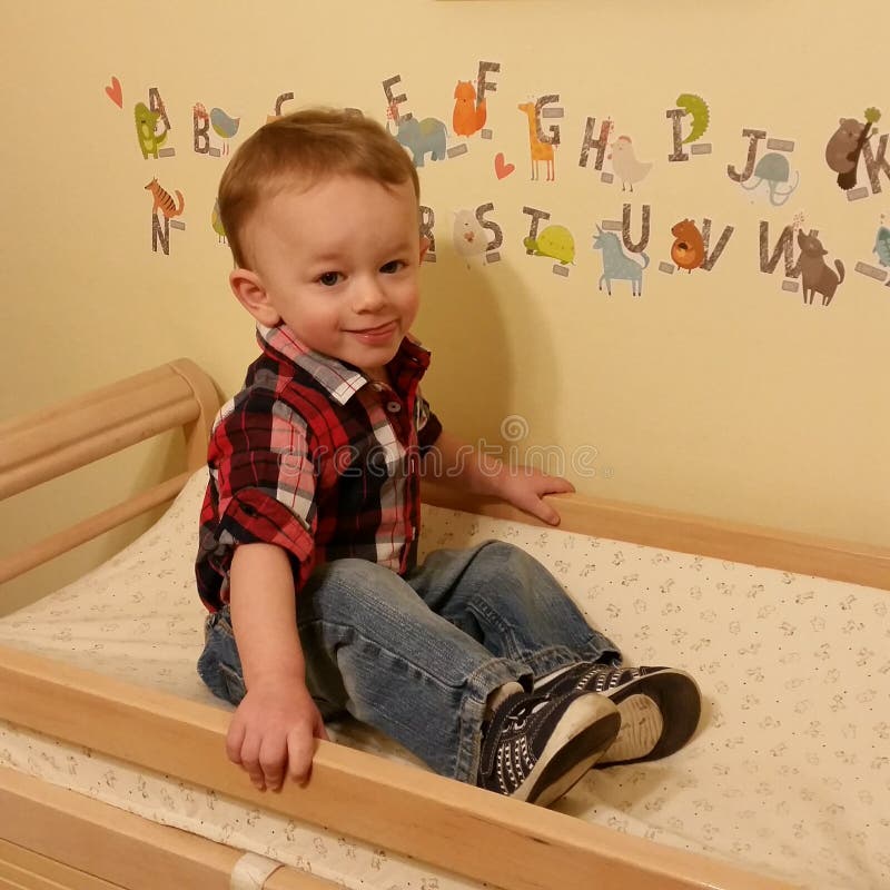 Niño pequeño que se sienta en una tabla cambiante foto de archivo libre de regalías Niño pequeño que se sienta en una tabla cambiante foto de archivo libre de regalías