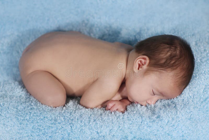 Niño pequeño recién nacido que duerme en un sistema lindo foto de archivo Niño pequeño recién nacido que duerme en un sistema lindo foto de archivo