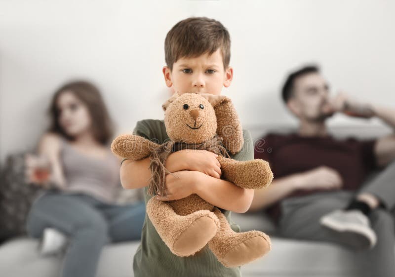 Niño pequeño trastornado que abraza el conejito del juguete mientras que sus padres que beben el alcohol imagenes de archivo Niño pequeño trastornado que abraza el conejito del juguete mientras que sus padres que beben el alcohol imagenes de archivo