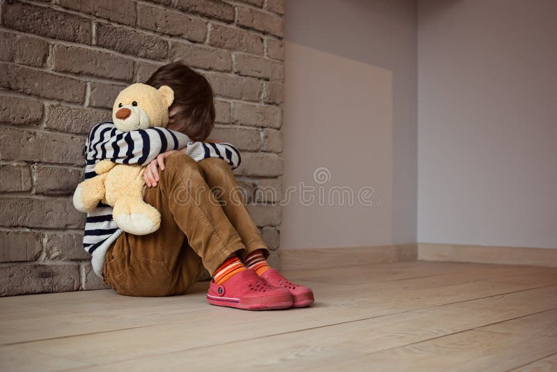 Niño pequeño triste que se sienta contra la pared en la desesperación imagen de archivo libre de regalías Niño pequeño triste que se sienta contra la pared en la desesperación imagen de archivo libre de regalías
