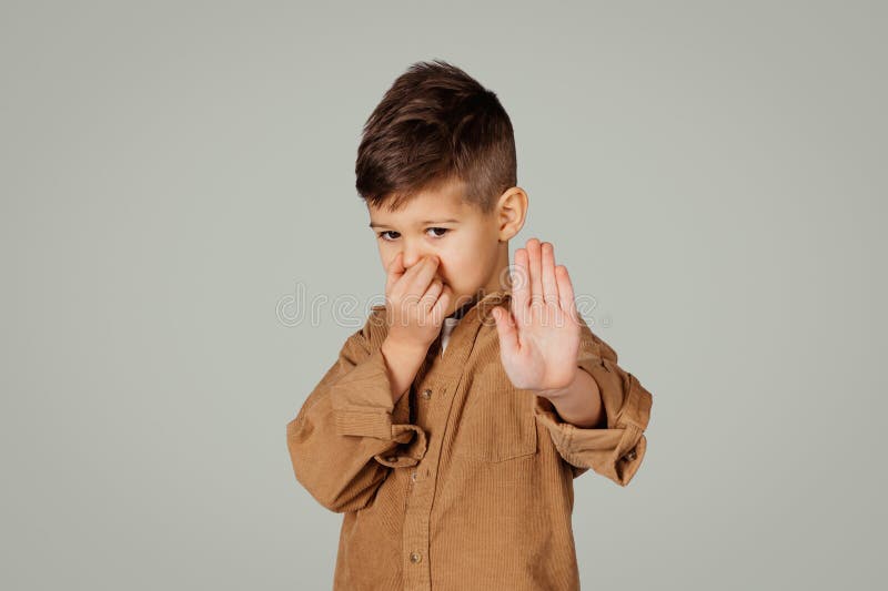 Niño pequeño y desesperado de 6 años en gesto casual de parada con las manos cierran la nariz