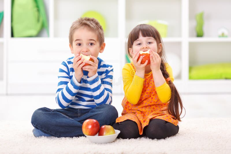 Niño pequeño y muchacha que comen manzanas fotos de archivo Niño pequeño y muchacha que comen manzanas fotos de archivo