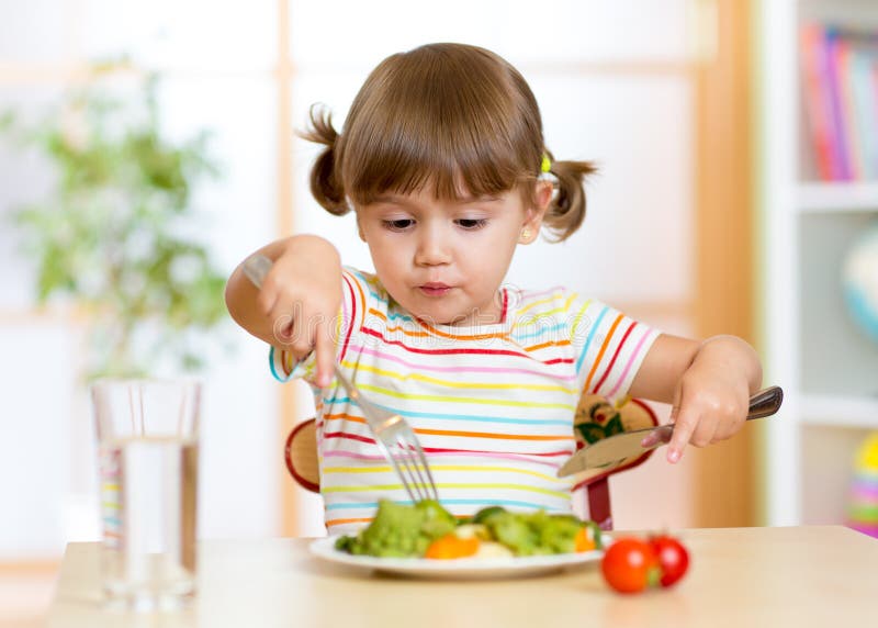 Niño que come la comida sana en casa o la guardería