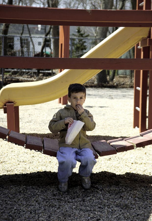 Niño que come las palomitas en el parque foto de archivo Niño que come las palomitas en el parque foto de archivo