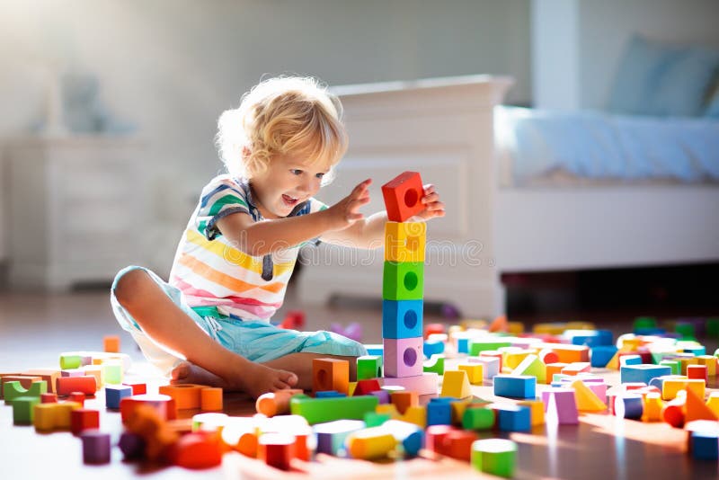Niño que juega con los bloques coloridos del juguete Juego de los niños