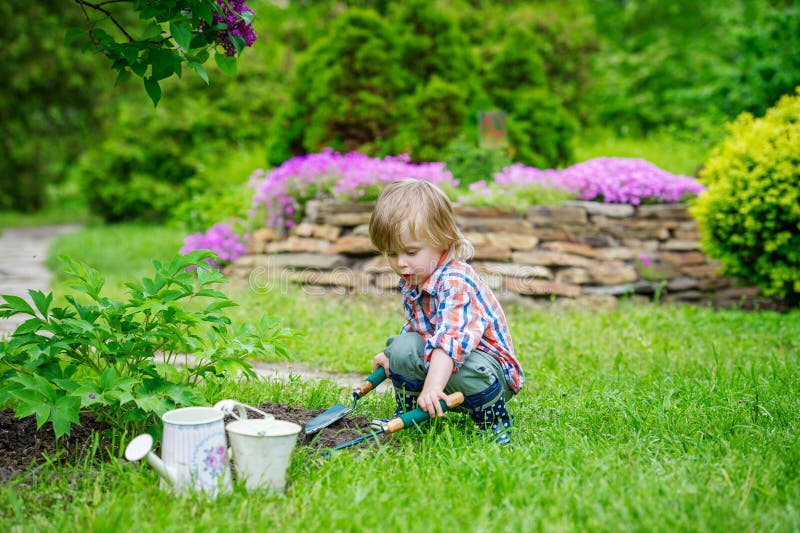 Niño que planta las flores en el jardín foto de archivo libre de regalías Niño que planta las flores en el jardín foto de archivo libre de regalías