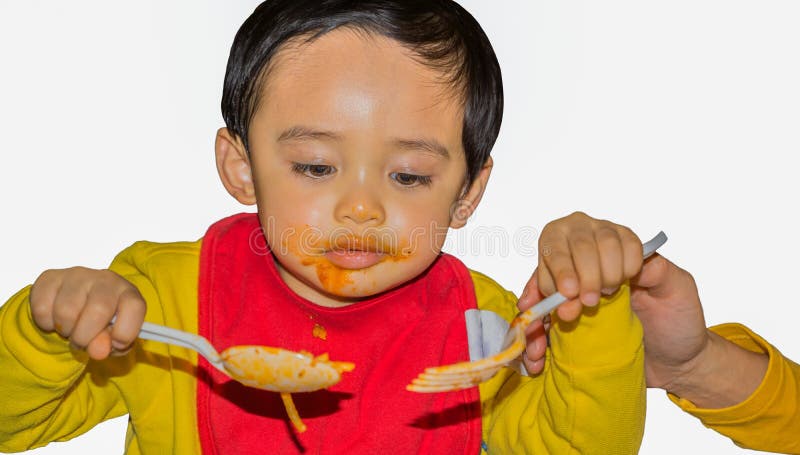 Niño que usa la cuchara y la bifurcación plásticas fotografía de archivo libre de regalías Niño que usa la cuchara y la bifurcación plásticas fotografía de archivo libre de regalías