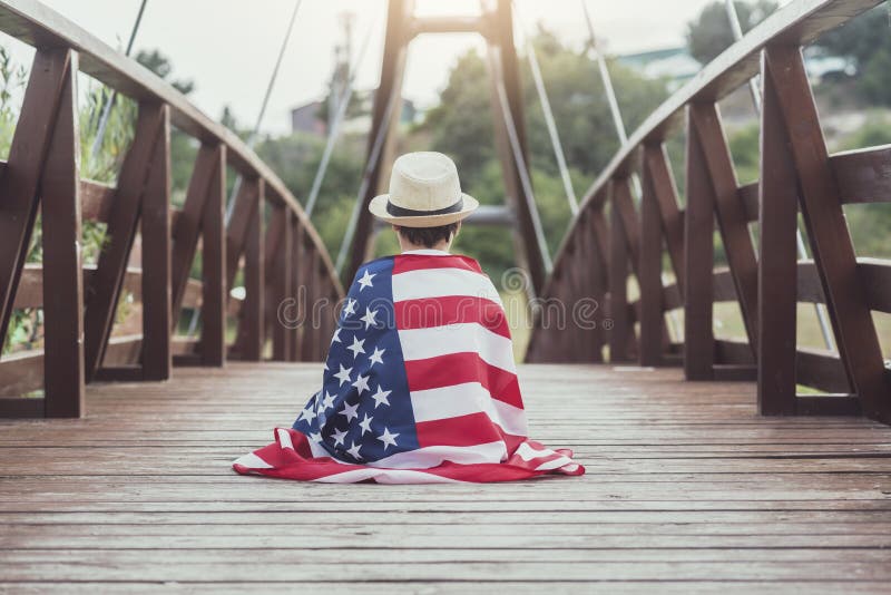 Niño triste con la bandera de los Estados Unidos foto de archivo libre de regalías Niño triste con la bandera de los Estados Unidos foto de archivo libre de regalías