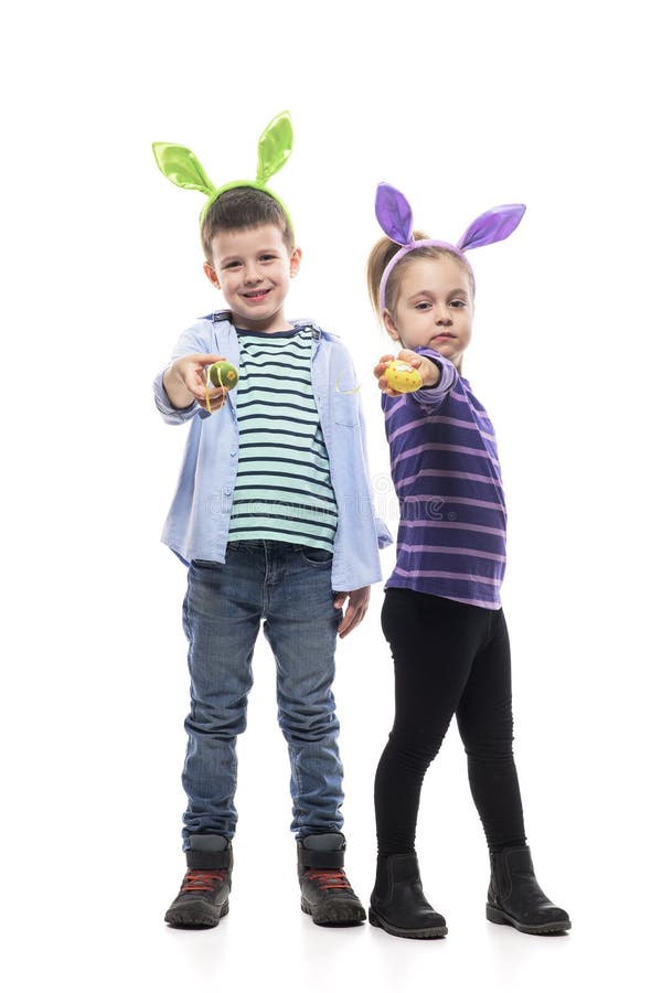 Niño y niña orgullosos con orejas de conejo mostrando huevos de pascua pintados a cámara. fotografía de archivo libre de regalías