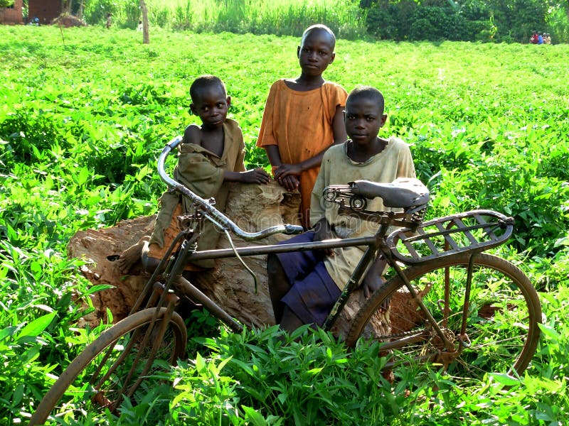Niños africanos que se colocan en los arbustos con su bici fotos de archivo libres de regalías Niños africanos que se colocan en los arbustos con su bici fotos de archivo libres de regalías
