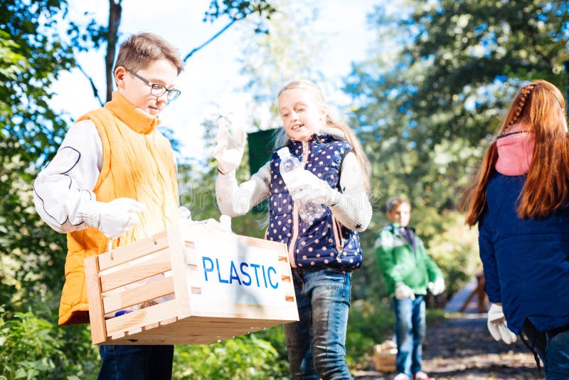 Niños agradables positivos que ayudan a limpiar el bosque imágenes de archivo libres de regalías