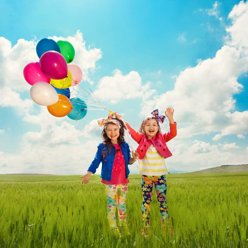 Niños con los globos que caminan en campo de la primavera fotos de archivo libres de regalías Niños con los globos que caminan en campo de la primavera fotos de archivo libres de regalías