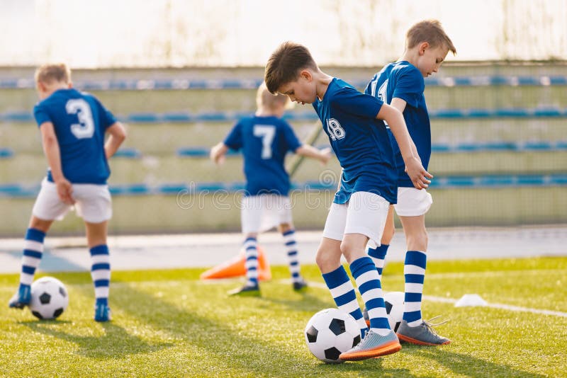 Niños de fútbol en equipo en unidad de práctica. escolares en entrenamiento de fútbol divirtiéndose juntos. jersey de fútbol azul fotografía de archivo libre de regalías
