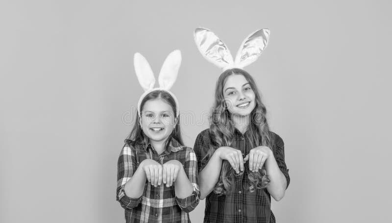 Niños de Pascua graciosos en orejas de conejito con fondo amarillo foto de archivo