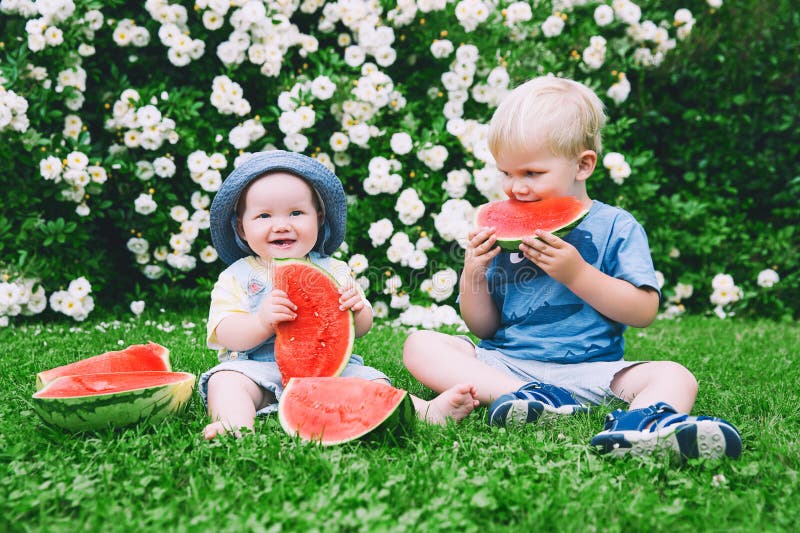 Niños divertidos que comen la sandía en la naturaleza en el verano foto de archivo libre de regalías Niños divertidos que comen la sandía en la naturaleza en el verano foto de archivo libre de regalías