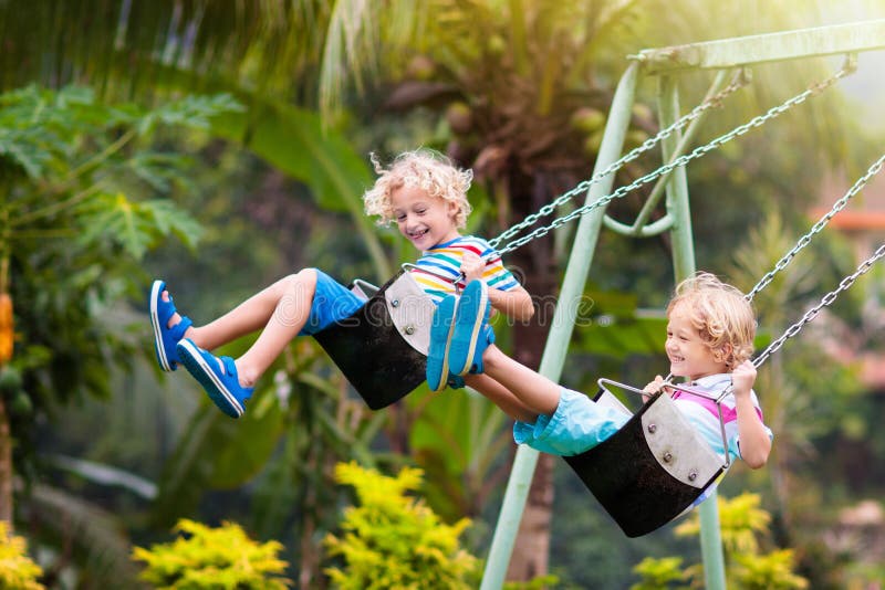 Niños en el área de juegos niños swing juegan al aire libre