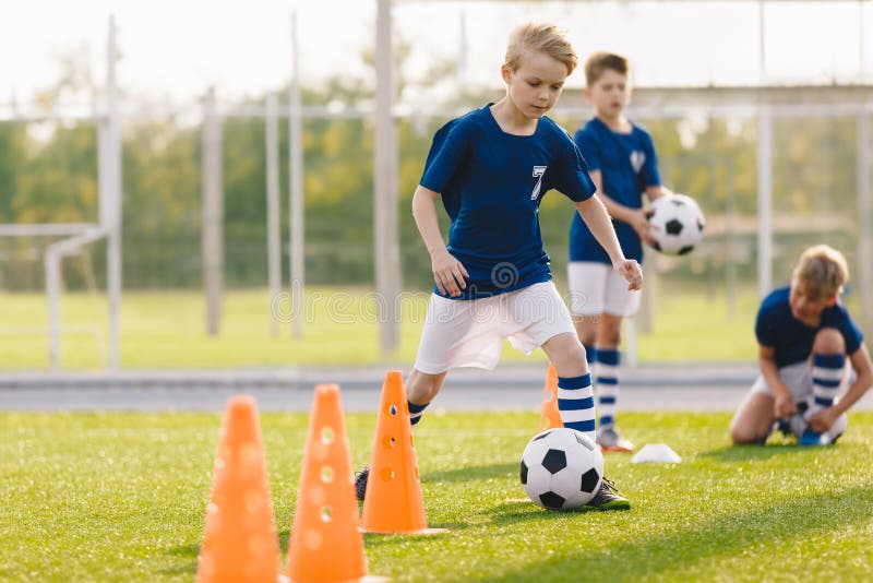 Niños en prácticas de fútbol. niños que asisten a cursos de fútbol en el campo escolar. niños de la clase de educación física fotos de archivo libres de regalías