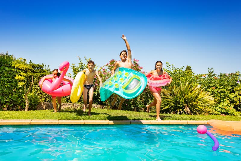 Niños felices que corren y que saltan en la piscina fotografía de archivo libre de regalías Niños felices que corren y que saltan en la piscina fotografía de archivo libre de regalías