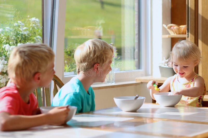 Niños felices que desayunan sano en la cocina fotografía de archivo libre de regalías Niños felices que desayunan sano en la cocina fotografía de archivo libre de regalías