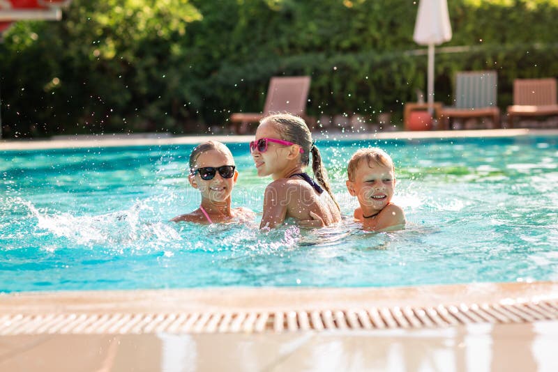 Niños felices que se divierten en la piscina imagen de archivo Niños felices que se divierten en la piscina imagen de archivo