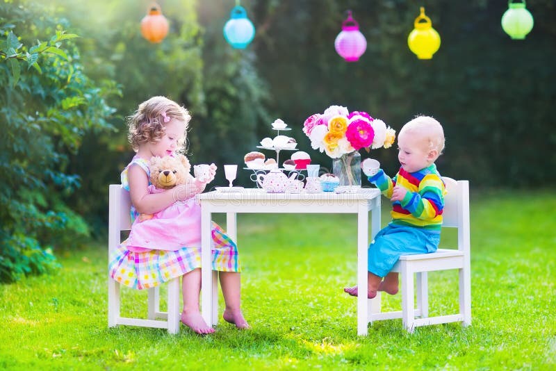 Niños hermosos en la fiesta del té de la muñeca fotografía de archivo Niños hermosos en la fiesta del té de la muñeca fotografía de archivo