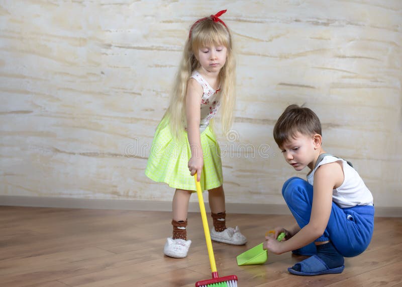 Niños lindos que usan la escoba y el recogedor de polvo del juguete imagen de archivo